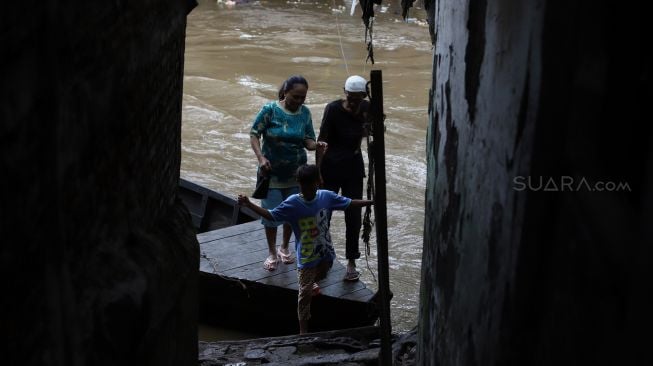 Penumpang turun dari perahu eretan usai menyeberangi Kali Ciliwung di kawasan Manggarai, Jakarta, Jumat (14/2). [Suara.com/Angga Budhiyanto]