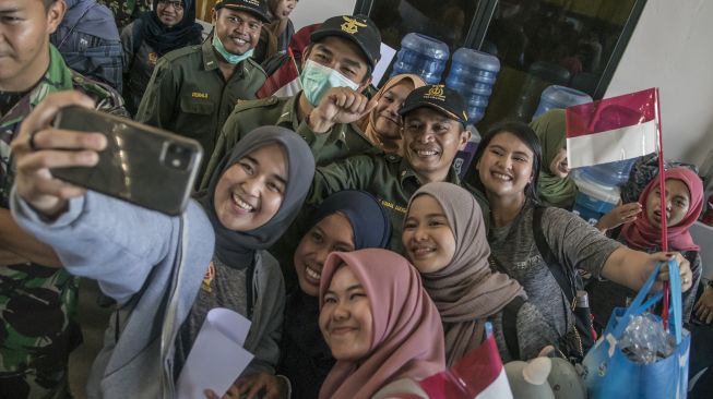 Warga Negara Indonesia (WNI) yang dievakuasi dari Wuhan, Provinsi Hubei, China berfoto bersama usai menjalani masa observasi di Hanggar Pangkalan Udara TNI AU Raden Sadjad, Ranai, Natuna, Kepulauan Riau, Sabtu (15/2). [ANTARA FOTO/Muhammad Adimaja]