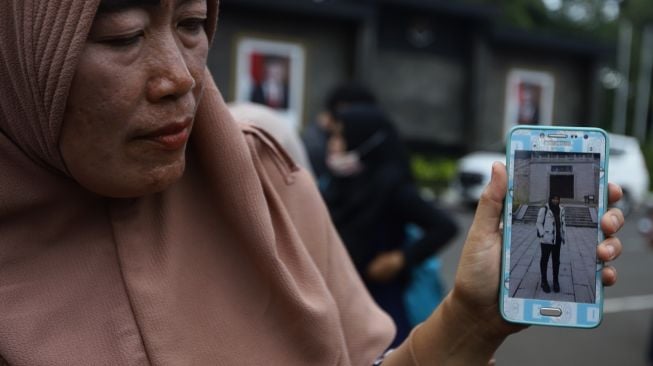 Salah seorang keluarga menunjukkan foto Warga Negara Indonesia (WNI) yang menjalani masa observasi selama 14 hari terkait virus corona di Pangkalan Udara TNI AU Raden Sadjad, Natuna, tiba di Bandara Internasional Halim Perdanakusuma, Jakarta, Sabtu (15/2). [Suara.com/Angga Budhiyanto]