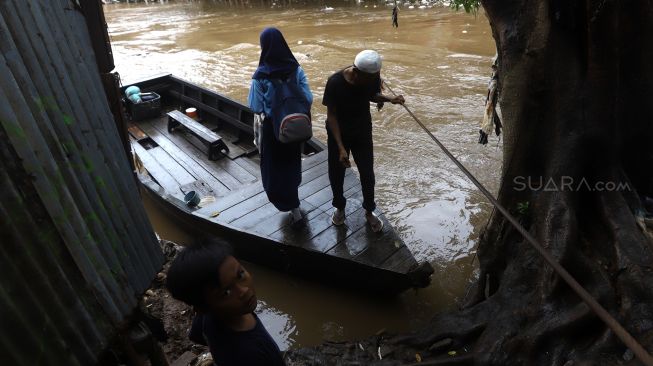 Warga menaiki perahu eretan untuk menyeberangi Kali Ciliwung di kawasan Manggarai, Jakarta, Jumat (14/2). [Suara.com/Angga Budhiyanto]