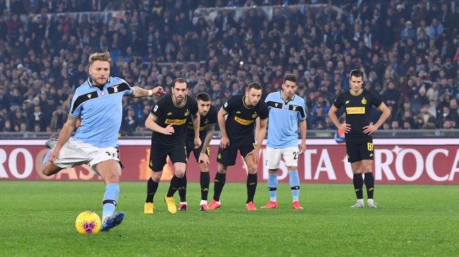 Pemain depan Lazio Ciro Immobile (kiri) menembak untuk mencetak penalti selama pertandingan sepak bola Serie A Italia, Lazio melawan Inter Milan di Stadion Olimpiko, Roma, Italia, Senin (17/2) dini hari WIB.
[Andreas SOLARO / AFP]