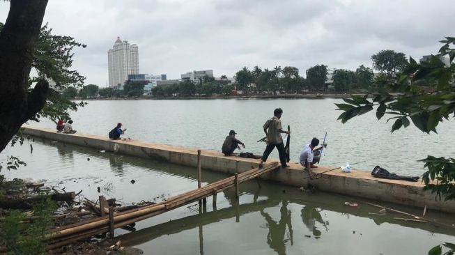 Pemancing di pinggir Danau Sunter. [Suara.com/Erick Tanjung]