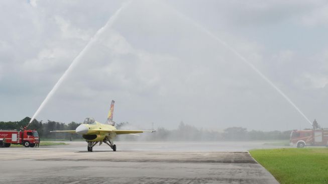 Penerbang dari pabrik pesawat Lockheed Martin Amerika Serikat bersama pesawat tempur F-16 mendapat water salute' atau semprotan air seusai test flight' perdana pesawat tersebut setelah menjalani upgrade' di Lanud Iswahjudi Magetan, Jawa Timur, Selasa (18/2).  [ANTARA FOTO/Siswowidodo]
