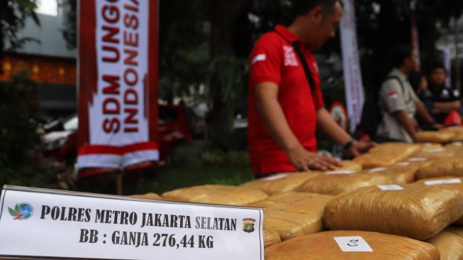 Petugas menaruh barang bukti narkotika di mesin pemusnah di Polda Metro Jaya, Jakarta Selatan, Rabu (19/02).[Suara.com/Alfian Winanto]