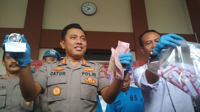 Kapolres Kudus AKBP Catur Gatot Efendi didampingi Kasat Reskrim AKP Rismanto menunjukkan barang bukti uang hasil penipuan berkedok penggandaan uang di Mapolres Kudus, Jawa Tengah, Rabu (19/2/2020). (ANTARA/Akhmad Nazaruddin Lathif)