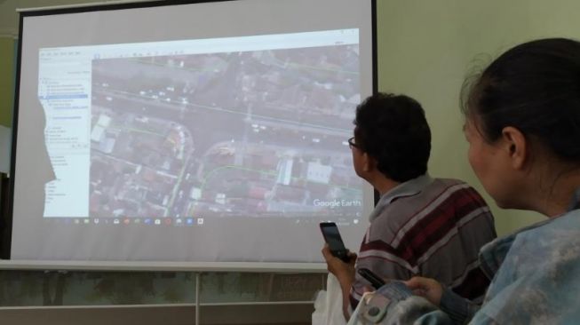 Sejumlah warga sedang mencermati dan mendokumentasikan desain tol Jogja, usai sosialisasi pembangunan tol di Balai Desa Sariharjo, Kecamatan Ngaglik, Kabupaten Sleman. - (Suara.com/Uli Febriarni)