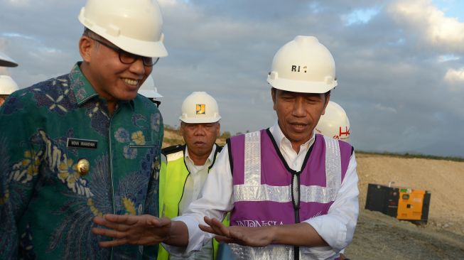 Presiden Joko Widodo (kanan) berbincang dengan Plt Gubernur Aceh Nova Iriansyah (kiri) saat meninjau perkembangan pembangunan Seksi IV jalan tol di Desa Indra Puri, Kabupaten Aceh Besar, Aceh, Jumat (21/2). [ANTARA FOTO/Ampelsa]