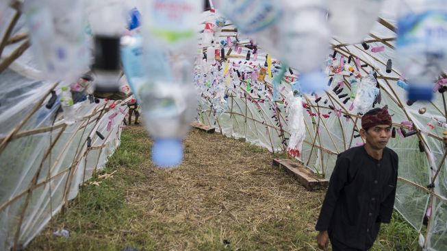 Warga kampung adat Cireundeu melintas di dalam terowongan plastik dari botol bekas di sela-sela upacara adat peringatan Hari Peduli Sampah Nasional (HPSN) 2020 di lokasi tragedi longsor sampah eks TPA Leuwigajah, Cimahi, Jawa Barat, Jumat (21/2). [ANTARA FOTO/M Agung Rajasa]