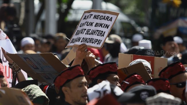 Massa aksi membawa poster saat aksi unjuk rasa terkait "Berantas Mega Korupsi, Selamatkan NKRI" di Jalan Merdeka Barat, Jakarta, Jumat (21/2). [Suara.com/Angga Budhiyanto]