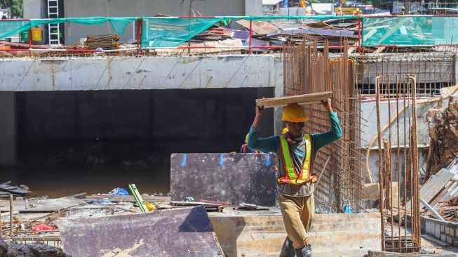 Pekerja membawa papan untuk menyelesaikan pembuatan jalur  terowongan yang akan menghubungkan Masjid Istiqlal dengan Gereja Katedral di Jakarta Pusat, Minggu (23/02).[Suara.com/Alfian 