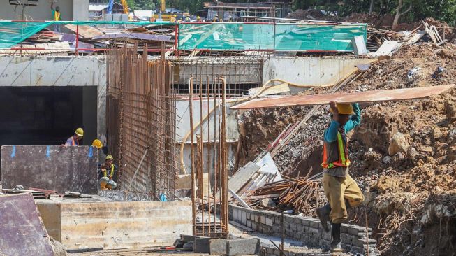 Pekerja membawa material papan untuk menyelesaikan pembuatan jalur  terowongan yang akan menghubungkan Masjid Istiqlal dengan Gereja Katedral di Jakarta Pusat, Minggu (23/02).[Suara.com/Alfian 