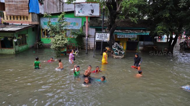 Aktivitas warga di rumahnya yang tergenang banjir di Petamburan II, Jakarta Pusat, Minggu (23/02). [Suara.com/Alfian Winanto]