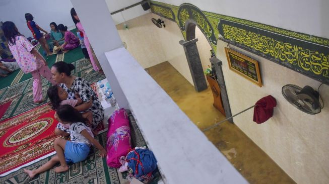 Sejumlah warga mengungsi di lantai dua Masjid Jami' Al-Jamaah yang juga terendam banjir di Jalan Anyer, Menteng, Jakarta, Minggu (23/2). [ANTARA FOTO/M Risyal Hidayat]
