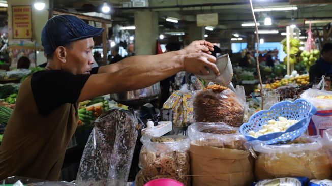 Pedagang membungkus bawang goreng dengan kantong plastik di Pasar Tradisional Pasar Minggu, Jakarta Selatan, Senin (24/02). [Suara.com/Alfian Winanto]
