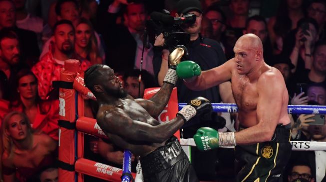 Petinju Inggris Tyson Fury (kanan) memberikan tekanan kepada juara bertahan kelas berat WBC, Deontay Wilder, dalam duel di MGM Grand Garden Arena, Las Vegas, AS, Sabtu (22/2/2020). Dalam duel itu Fury menang TKO ronde ketujuh atas Wilder. [AFP/Mark Ralston]