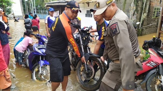 Warga dibantu petugas Satpol PP mengevakuasi sejumlah kendaraan akibat banjir di Cipinang Melayu, Jakarta Timur, Selasa (25/2/2020). (Suara.com/Stephanus Aranditio)