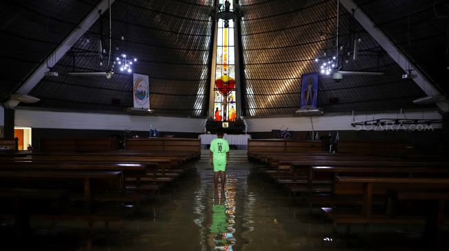 Seorang anak berjalan di dalam Gereja Santo Kristoforus yang terendam banjir di kawasan Jalan Satria IV, Kelurahan Jelambar, Jakarta Barat, Selasa (25/2).  [Suara.com/Angga Budhiyanto]  