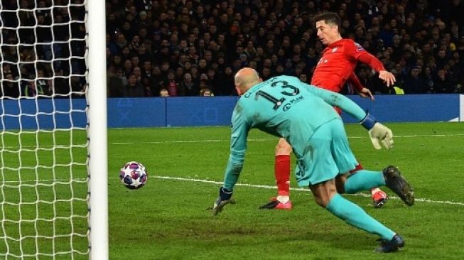 Striker Bayern Munich Robert Lewandowski mencetak gol setelah menaklukkan kiper Chelsea Willy Caballero saat leg pertama babak 16 besar Liga Champions di Stamford Bridge. Glyn KIRK / AFP