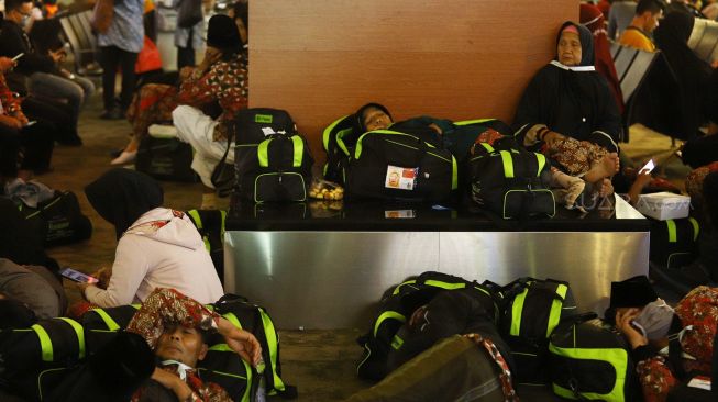 Calon Jamaah Umroh tertidur saat menunggu kepastian pemberangkatan ke Tanah Suci Mekah di Terminal 3 Bandara Soekarno Hatta, Tangerang, Banten, Kamis (27/2). [Suara.com/Angga Budhiyanto]