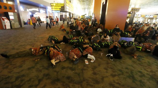 Sejumlah calon Jamaah Umroh tertidur saat menunggu kepastian pemberangkatan ke Tanah Suci Mekah di Terminal 3 Bandara Soekarno Hatta, Tangerang, Banten, Kamis (27/2). [Suara.com/Angga Budhiyanto