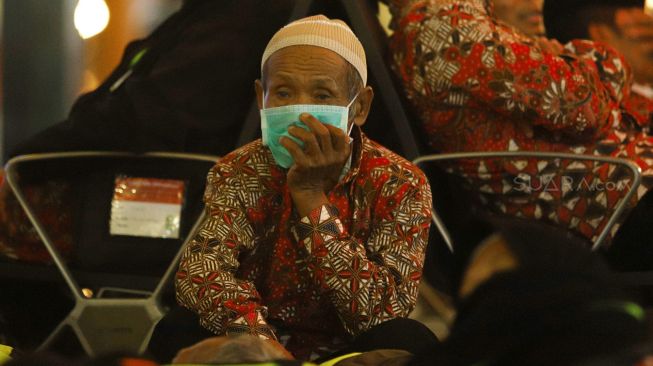 Calon Jamaah Umroh merenung dan menunggu kepastian pemberangkatan ke Tanah Suci Mekah di Terminal 3 Bandara Soekarno Hatta, Tangerang, Banten, Kamis (27/2). [Suara.com/Angga Budhiyanto]