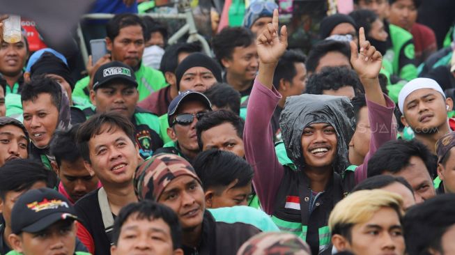 Ekspresi salah seorang pendemo  mendengarkan orasi saat driver Ojol (Ojek Online) berunjuk rasa di depan Gedung DPR dan MPR RI, Jakarta, Jumat (28/02). [Suara.com/Alfian Winanto]