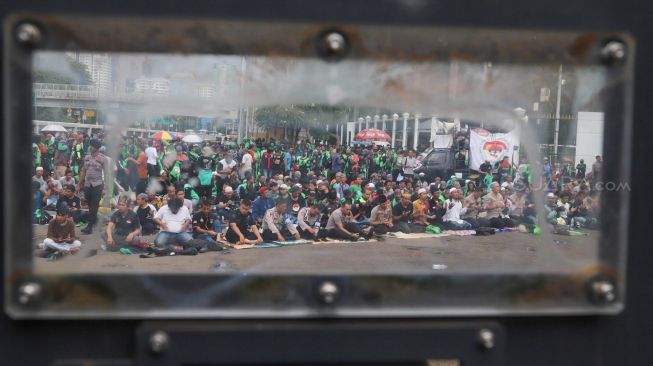 Para pengemudi Ojol (Ojek Online) menggelar Salat Jumat bareng Polisi di depan Gedung  DPR dan MPR RI, Jakarta, Jumat (28/02). [Suara.com/Alfian Winanto]
