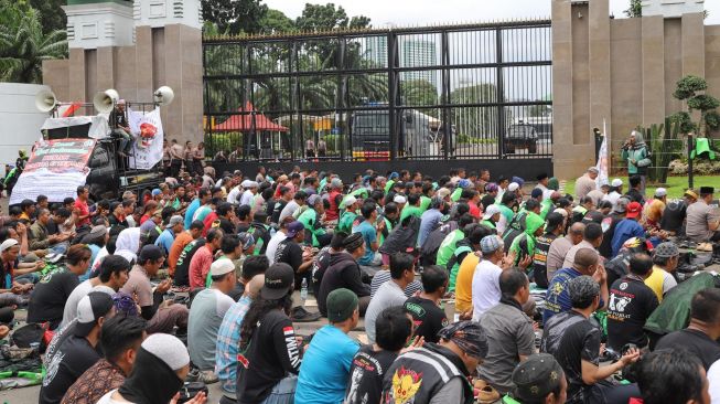 Para pengemudi Ojol (Ojek Online) menggelar Salat Jumat bareng Polisi di depan Gedung  DPR dan MPR RI, Jakarta, Jumat (28/02). [Suara.com/Alfian Winanto]
