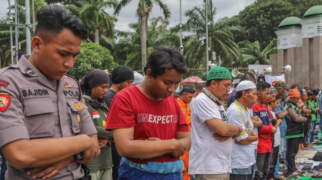 Para pengemudi Ojol (Ojek Online) Salat Jumat bareng Polisi di depan Gedung  DPR dan MPR RI, Jakarta, Jumat (28/02). [Suara.com/Alfian Winanto]
