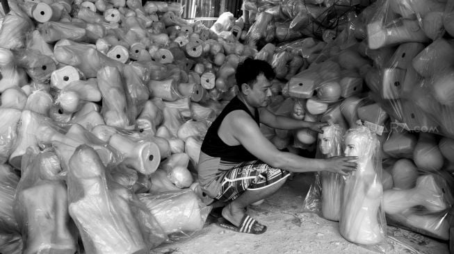 Egi Suherman merapikan tumpukan boneka manekin di gudang bengkel rias manekin miliknya, di Jalan Prepedan Dalam, Kalideres, Jakarta Barat, Kamis (27/02). [Suara.com/Alfian Winanto]