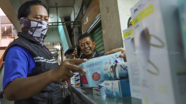Pembeli memilih masker yang akan dibelinya di Pasar Pramuka,  Jakarta Timur, Senin (2/3). [Suara.com/Alfian Winanto]