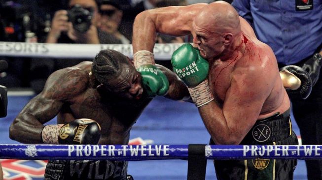 Petinju Inggris, Tyson Fury (kanan), mendaratkan pukulan telak ke wajah juara dunia kelas berat WBC, Deontay Wilder, dalam duel di MGM Grand Garden Arena, Las Vegas, Sabtu (22/2/2020). [AFP/John Gurzinski]