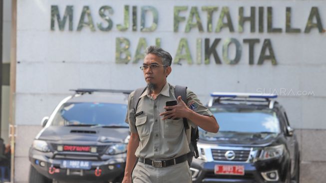 Seorang ASN melewati Masjid Fatahillah di kawasan  gedung Balaikota DKI Jakarta, Jakarta Pusat, Senin (2/3). [Suara.com/Alfian Winanto]