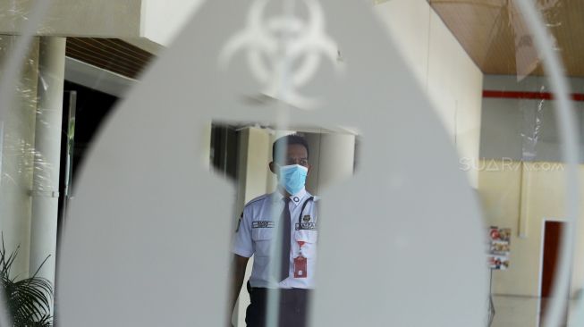 Seorang petugas keamanan mengenakan masker saat berada di area Rumah Sakit Penyakit Infeksi (RSPI) Prof. Dr. Sulianti Saroso, Sunter, Jakarta Utara, Senin (2/3).  [Suara.com/Angga Budhiyanto]