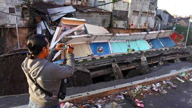 Seorang jurnalis mengambil gambar pertokoan Jompo yang ambruk di Jalan Sultan Agung Jember, Jawa Timur, Senin (2/3). [ANTARA FOTO/Seno]
