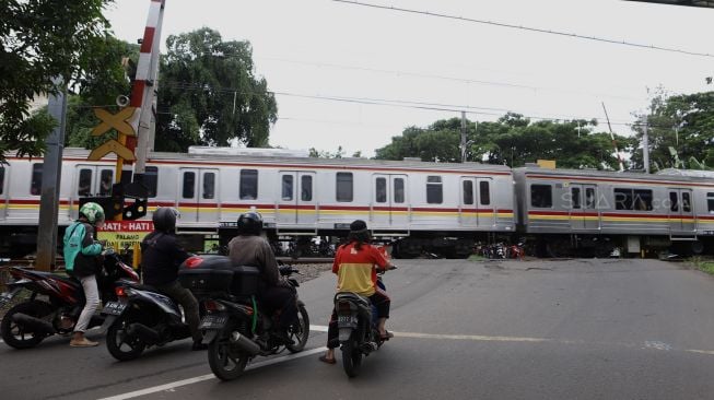 Pengendara menunggu kereta melintas di pelintasan kereta Bumi Bintaro Permai, Pesanggrahan, Jakarta Selatan, Senin (2/3).  [Suara.com/Angga Budhiyanto]