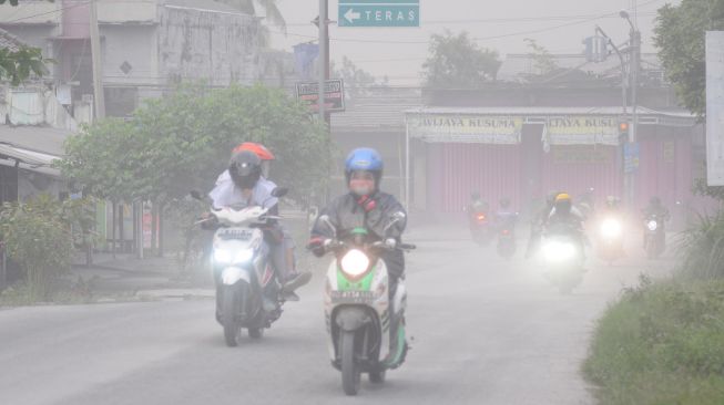 Pengendara motor menutup wajahnya saat melintas dan terjadi hujan abu di Mojosongo, Boyolali, Jawa Tengah, Selasa (3/3).  [ANTARA FOTO/Aloysius Jarot Nugroho]
