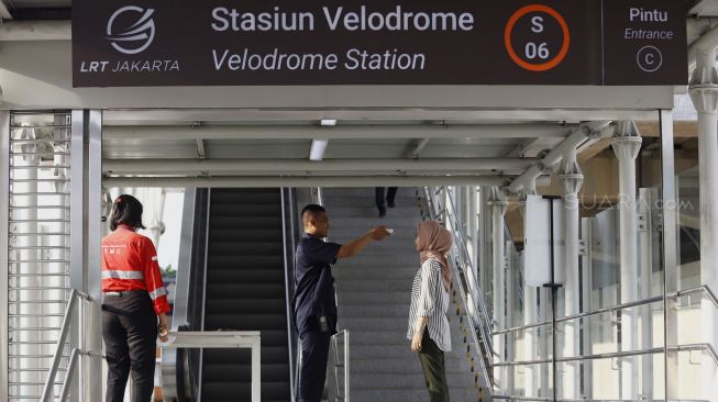 Petugas melakukan pengecekan suhu tubuh seorang calon penumpang sebelum memasuki Stasiun LRT Velodrome, Rawamangun, Jakarta Timur, Selasa (3/3). [Suara.com/Angga Budhiyanto]