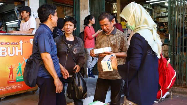 Pembeli membayar masker yang dibelinya di Pasar Pramuka,  Jakarta Timur, Senin (2/3). [Suara.com/Alfian Winanto]

