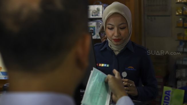 Petugas melayani pembeli masker di apotek Kimia Farma Menteng, Jakarta, Rabu (4/3). [Suara.com/Angga Budhiyanto]