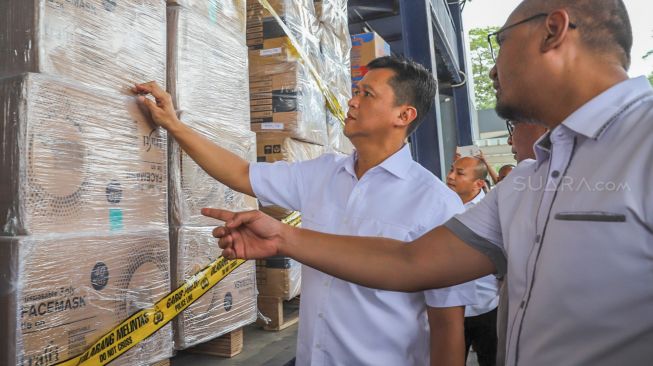 Dirkrimsus Polda Metro Jaya Kombes Pol Iwan Kurniawan mengecek timbunan masker di gudang PT MJP Cargo, Tangerang, Jawa Barat, Rabu (4/3). [Suara.com/Alfian Winanto]