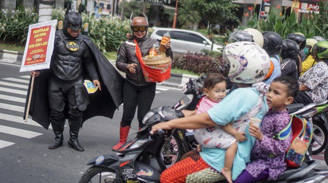 Warga dengan mengenakan kostum tokoh superhero batman dan gundala melakukan aksi sosialisasi pencegahan virus corona dan mambagikan jamu kepada pengguna jalan di Solo Baru, Sukoharjo, Jawa Tengah, Rabu (4/3).  [ANTARA FOTO/Mohammad Ayudha]
