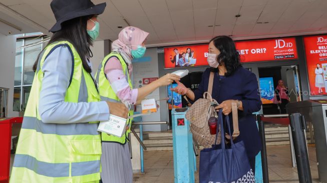 Petugas wanita membagikan masker ke pengguna Commuterline di Stasiun Depok Baru, Depok, Jawa Barat, Selasa (3/3). [Suara.com/Alfian Winanto]