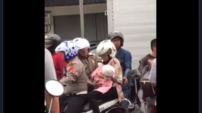 Seorang petugas polisi tolong ibu dan bayi yang terjebak ricuh ojol dan sekelompok massa di Babarsari, Sleman, Kamis (5/3/2020). [@devyyyy____ / Twitter]