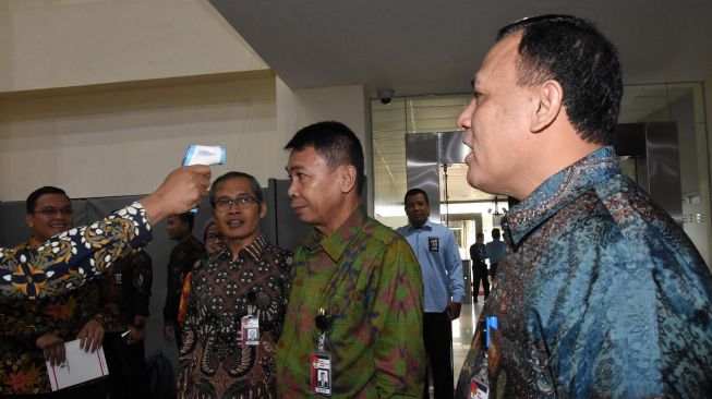 Petugas memeriksa suhu tubuh Ketua KPK Firly Bahuri (kanan), Wakil Ketua Nawawi Pomolango (tengah), dan Alexander Marwata (kiri) di Gedung Merah Putih KPK, Jakarta, Kamis (5/3).  [ANTARA FOTO/Indrianto Eko Suwarso]