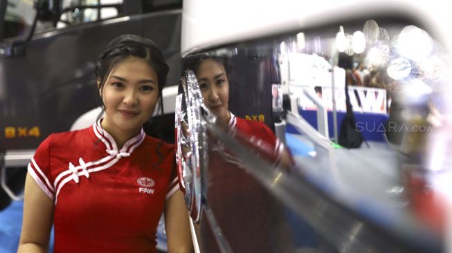 Refleksi model berpose di depan truk yang dipamerkan di pameran otomotif GAIKINDO Indonesia International Commercial Vehicle Expo (GIICOMVEC) di Jakarta Convention Center (JCC), Jakarta, Kamis (5/3). [Suara.com/Angga Budhiyanto]
