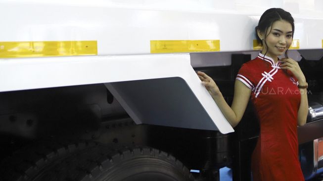 Seorang model berpose disamping truk yang dipamerkan di pameran otomotif GAIKINDO Indonesia International Commercial Vehicle Expo (GIICOMVEC) di Jakarta Convention Center (JCC), Jakarta, Kamis (5/3). [Suara.com/Angga Budhiyanto] 