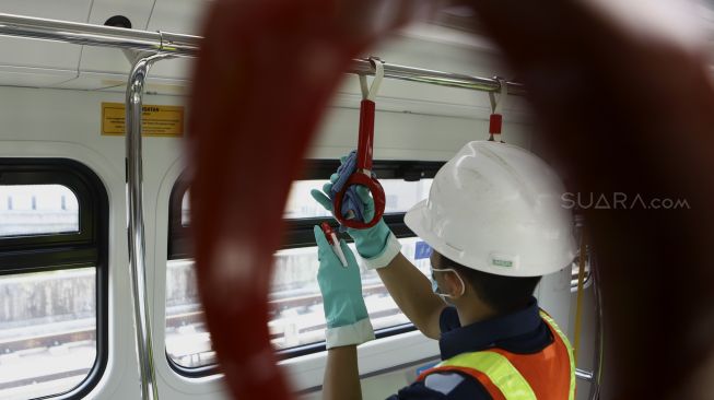 Petugas membersihkan bagian dalam pada rangkaian kereta Light Rapid Transit (LRT) di Depo LRT Jakarta, Kelapa Gading, Jakarta Timur, Jumat (6/3).  [Suara.com/Angga Budhiyanto]

