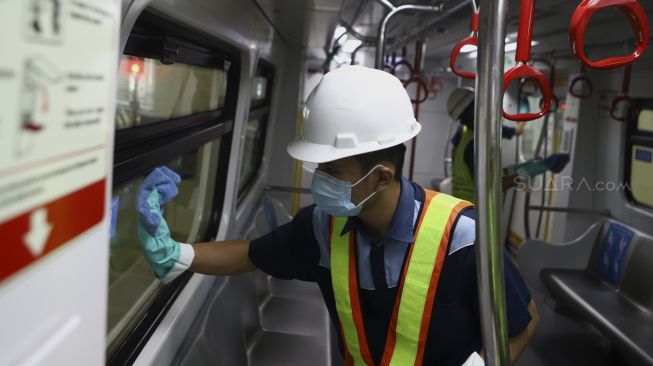 Petugas membersihkan jendela dalam pada rangkaian kereta Light Rapid Transit (LRT) di Depo LRT Jakarta, Kelapa Gading, Jakarta Timur, Jumat (6/3).  [Suara.com/Angga Budhiyanto]

