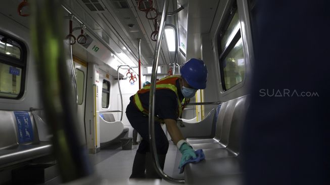 Petugas membersihkan kursi pada rangkaian kereta Light Rapid Transit (LRT) di Depo LRT Jakarta, Kelapa Gading, Jakarta Timur, Jumat (6/3).  [Suara.com/Angga Budhiyanto]

